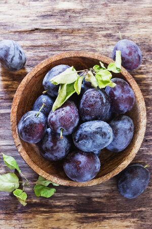 Ripe plums in a wooden bowl on the table. Bio healthy fruits. Concept of healthy food.View from aboveの写真素材