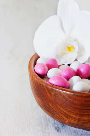 Different colored candies covered with glaze in a wooden bowl  on a white wooden background. Holidays and events. Sweet table. Selective focusの写真素材