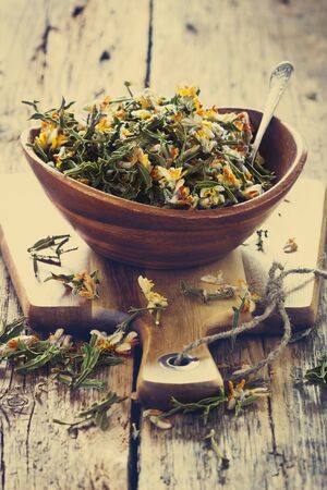 Dried medicinal herbs  in a  bowl on a wooden table.( Carqueja and Genista Tridentata). Alternative treatment . Selective focus. Toned imageの写真素材