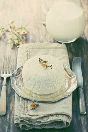 Traditional homemade cottage cheese in a plate on the old wooden background. Helpful dairy products....
