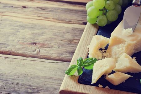 Fresh parmesan cheese and ripe grapes on a table. Tinted image. Health and diet food. Selective focus. Copy space for you textの写真素材