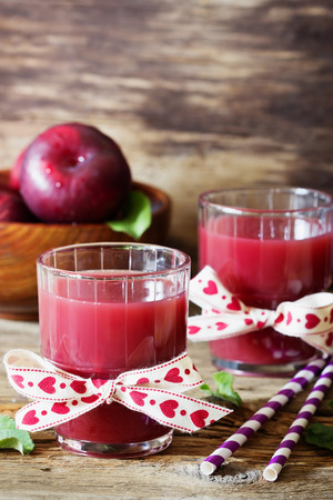 Useful plum juice in a glass on a wooden background. Healthy and diet drink. Selective focusの写真素材