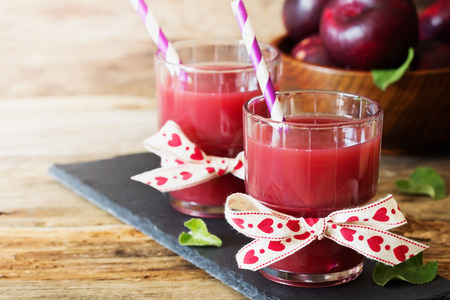 Useful plum juice in a glass on a wooden background. Healthy and diet drink. Selective focusの写真素材