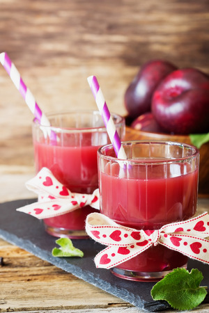 Useful plum juice in a glass on a wooden background. Healthy and diet drink. Selective focusの写真素材
