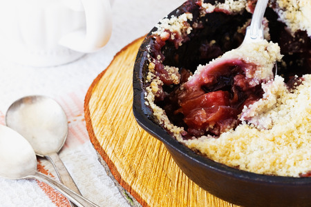 Plum crumble in a frying pan on the table. Traditional English cuisine. Selective focusの写真素材