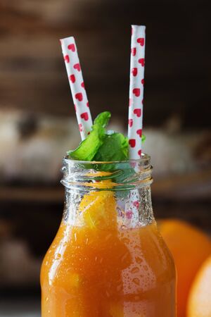 Fruit juice in a glass bottle and fresh sliced fruits on a wooden background. Healthy eating and healthy lifestyle. Close-upの写真素材