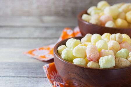 Colored corn balls in a wooden bowl on a wooden background. Healthy eatingの写真素材