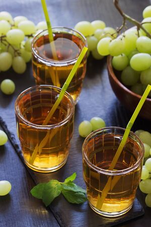 Summer grape juice in a glass and fresh grapes on a wooden background. Healthy eatingの写真素材