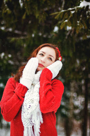 Beautiful young woman portrait in red clothes in frosty winter parkの写真素材