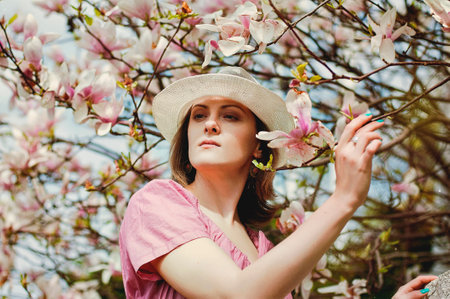 Portrait of young attractive woman in spring garden with blooming magnolias. Spring background....