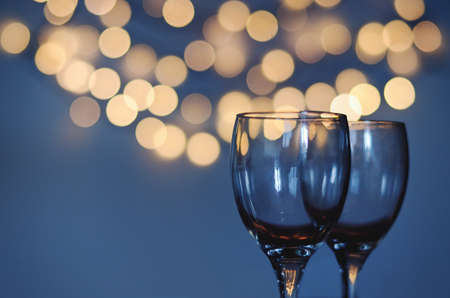 Empty glasses of wine on glass table with bokeh background close up. New Year, Christmas mood. Greeting card. Party and holiday celebration concept.の写真素材