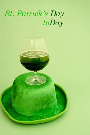 Happy St Patrick's Day concept. Glass of green beer and party hat in green background. Greeting...