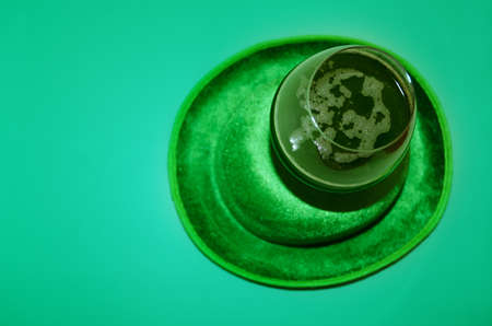 Happy St Patrick's Day concept. Glass of green beer and party hat in green background. Greeting card. Copy space. Flat lay.の写真素材