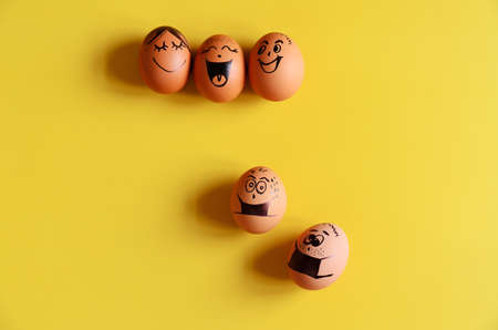 Creative Easter chicken eggs with doodle faces wearing medical masks on yellow background. Flat lay, top view, mockup, copy space.の写真素材