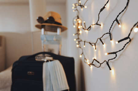 Travel preparations after the end of quarantine. New life after pandemic and prevent coronavirus (COVID-19) concept. Medical face masks, gloves, sanitizer, sunglasses and beach hat on baggage close upの写真素材