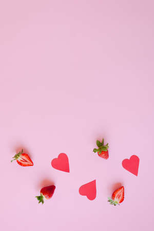 Festive pink background. Red paper hearts and fresh strawberries. Love. Valentine's Day. 14 of February. Creative greeting card. Flat lay, top view.の写真素材