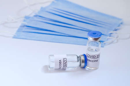 Creative ideas of vaccination concept. Top view of syringe with medical masks and vaccine vial glass...