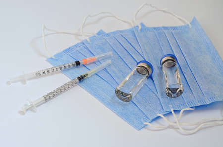 Creative ideas of vaccination concept. Top view of syringe with medical masks and vaccine vial glass bottles for vaccinationの写真素材