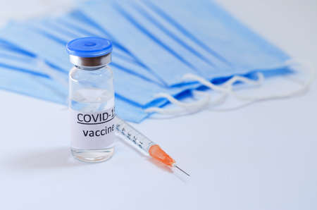 Creative ideas of vaccination concept. Top view of syringe with medical masks and vaccine vial glass...