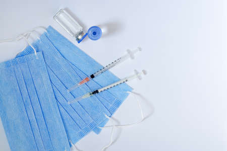 Top view of syringe with medical masks and vaccine vial glass bottles for vaccination