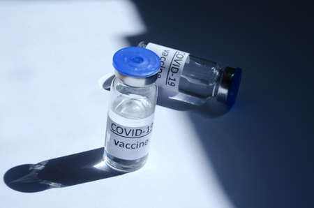 Creative ideas of vaccination concept. Top view of syringe with medical masks and vaccine vial glass bottles for vaccination against COVID-19. Coronavirus pandemic. Copy space.の写真素材