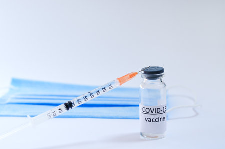 Creative ideas of vaccination concept. Top view of syringe with medical masks and vaccine vial glass bottles for vaccination against COVID-19. Coronavirus pandemic. Copy space.の写真素材