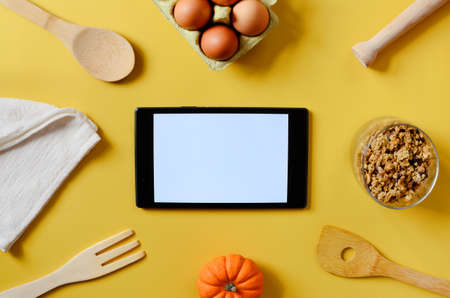 Flat lay with tablet with white mockup and place for text on yellow background. Food blogger's...