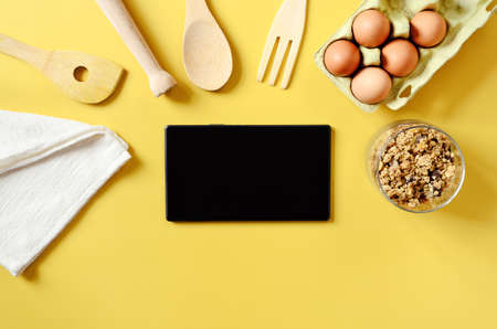 Flat lay with tablet with black mockup and place for text on yellow background. Food blogger's workplace. Culinary blog, recipe template, online cooking courses. Healthy food concept. Copy space.の写真素材