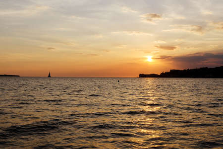 Picturesque seaside resort town in Slovenian coast against orange sunset sky in summer. Scenic view to Adriatic sea in the evening. Travel concept.の写真素材