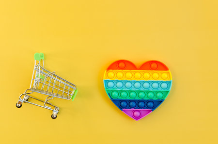 Top view of colorful markers and anti stress sensory toy pop it rainbow heart on yellow background close up. Creative and funny concepts of children toys. Popular toy. Trend toy 2021 year.の写真素材