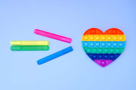 Top view of colorful anti stress sensory toy pop it rainbow heart on blue background close up. Creative and funny concepts of children toys. Popular toy. Trend toy 2021 year.の写真素材