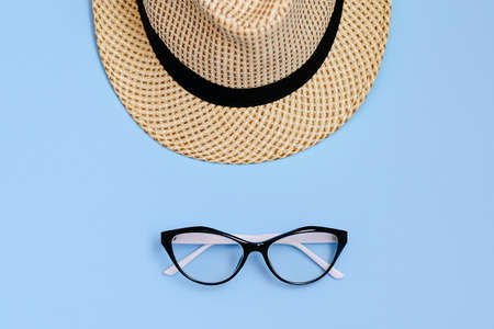 Flat lay with sunglasses, straw boater hat and bright big yellow sunflower on blue background. Travel summer concept. Copy space.の写真素材