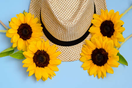 Flat lay with sunglasses, straw boater hat and bright big yellow sunflower on blue background. Travel summer concept. Copy space.の写真素材