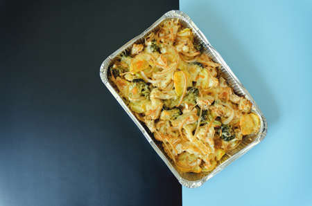 Top view of vegan vegetable casserole with potatoes, broccoli, onions, cauliflower greens close up....