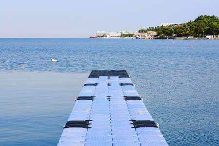 The pier near beach against blue sky in sunny day. Adriatic coast and sea in Slovenia. Holiday and travel concept.の写真素材