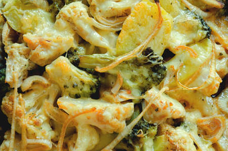 Top view of vegan vegetable casserole with potatoes, broccoli, onions, cauliflower greens close up. Baked in oven potatoes. Healthy homemade vegetarian food.の写真素材