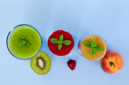 Top view of different fresh delicious smoothies in a glasses made of peach, banana and berries with mint. Creative concept of healthy detox drink, diet or vegetarian food concept. Copy space.の写真素材
