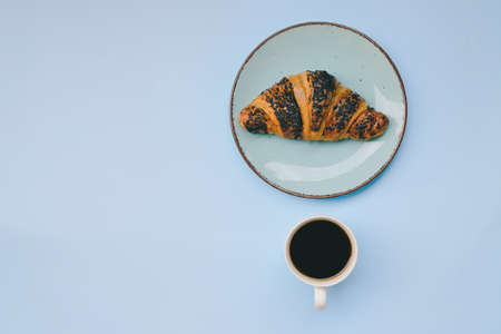 Businessman working morning with cups of hot black coffee and sweet croissant on blue background. Top view, copy space, mockup. Flat lay. Healthy food concept. Modern breakfast food.の写真素材