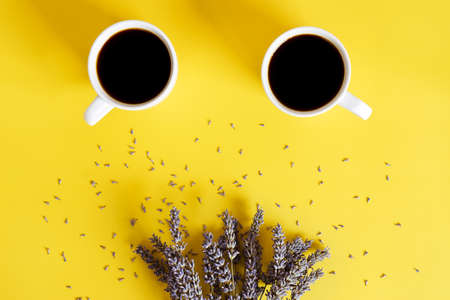 Businessman working morning with cups of hot black coffee and lavender bouquet on yellow background. Top view, copy space, mockup. Flat lay. Spring and modern breakfast food concept.の写真素材