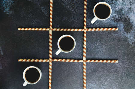 Businessman working morning with cups of hot coffee and sweet croissants on black background. Game...