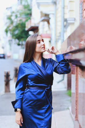 Urban fashion portrait of a stylish young business woman in a long blue dress and with long dark hair.の写真素材