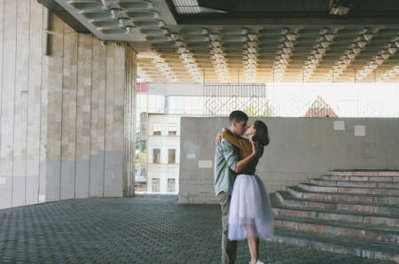 Kharkiv, Ukraine. 09.19.2021. Love story of stylish funny couple: young man in a t-shirt. And a cute young woman in wedding white skirt and yellow sweater. Family holiday and togetherness, dateの写真素材