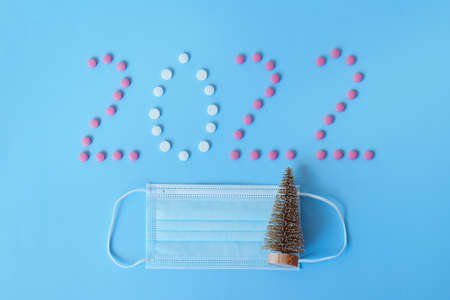 Christmas, New Year flat lay on blue background. numbers 2022 making with pills and medical mask. Top view. Copy space. Mock up. Concept of health care. New normal life after COVID-19. Copy space.の写真素材