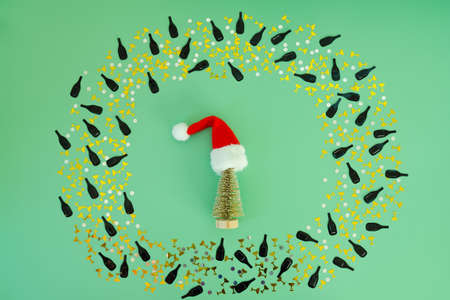 Christmas flat lay on green background with place for text. Christmas hat and toy tree, confetti,...