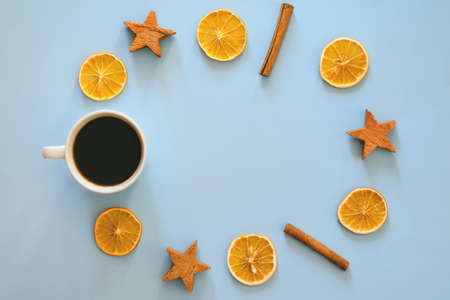 Christmas, New Year flat lay on blue background. Christmas decorations with dry spices, orange rings, cinnamon. Cup of hot black coffee. writing board, notebook paper. Top view. Copy space. Mock upの写真素材