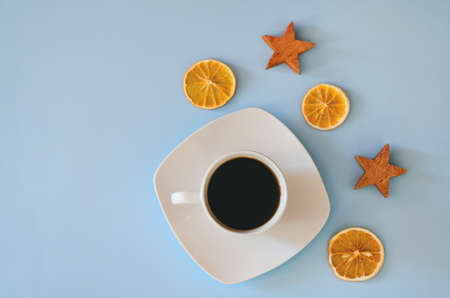 Christmas, New Year flat lay on blue background. Christmas decorations with dry spices, orange rings, cinnamon. Cup of hot black coffee. writing board, notebook paper. Top view. Copy space. Mock upの写真素材