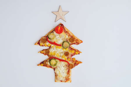 Delicious vegetarian Christmas tree pizza with tomatoes, vegetables and cheese on white background. Creative, funny food concept for kids. Top view, flat lay. Copy space.の写真素材