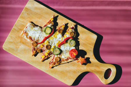 Pizza on a cutting board on a pink background, top viewの写真素材