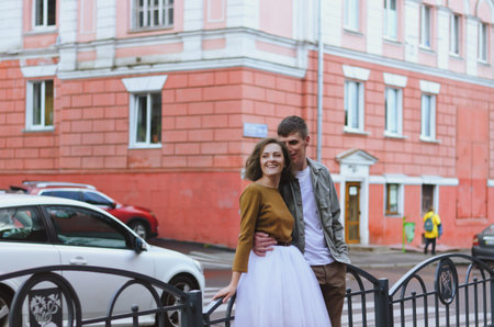 Kharkiv, Ukraine. 09.19.2021. Love story of stylish funny couple: young man in a t-shirt. And a cute young woman in wedding white skirt and yellow sweater. Family holiday and togetherness, dateのeditorial素材