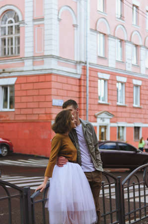 Kharkiv, Ukraine. 09.19.2021. Love story of stylish funny couple: young man in a t-shirt. And a cute young woman in wedding white skirt and yellow sweater. Family holiday and togetherness, dateのeditorial素材